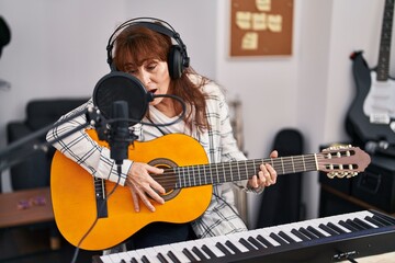 Sticker - Middle age woman musician singing song playing spanish guitar at music studio