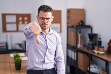 Poster - Young hispanic man at the office looking unhappy and angry showing rejection and negative with thumbs down gesture. bad expression.