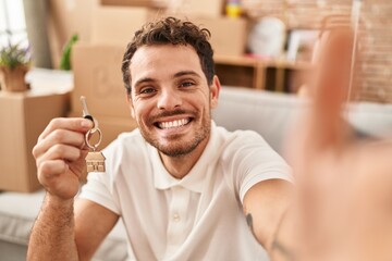 Sticker - Young hispanic man make selfie by the camera holding key at new home