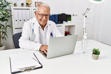 Canvas Print - Senior man wearing doctor uniform working at clinic