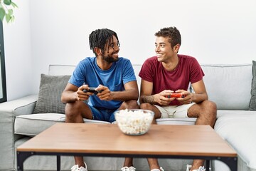 Poster - Two men friends playing video game sitting on sofa at home