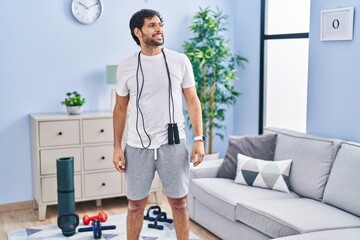 Canvas Print - Handsome latin man wearing sportswear at home looking away to side with smile on face, natural expression. laughing confident.