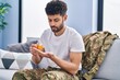 © Krakenimages.com - Young arab man army soldier taking pills sitting on sofa at home