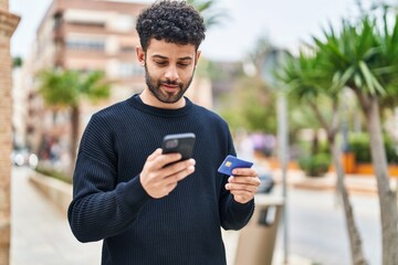 Canvas Print - Young arab man using smartphone and credit card at street