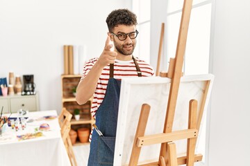 Canvas Print - Arab young man at art studio pointing fingers to camera with happy and funny face. good energy and vibes.