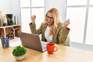 Sticker - Beautiful blonde woman working at the office with laptop very happy and excited doing winner gesture with arms raised, smiling and screaming for success. celebration concept.