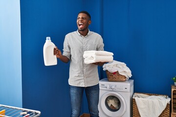 Wall Mural - African american man holding clean towels angry and mad screaming frustrated and furious, shouting with anger. rage and aggressive concept.