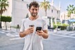 © Krakenimages.com - Young hispanic man using smartphone drinking coffee at street