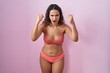 Young hispanic woman wearing lingerie over pink background angry and mad raising fists frustrated and furious while shouting with anger. rage and aggressive concept.
