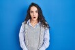 © Krakenimages.com - Young brunette woman standing over blue background afraid and shocked with surprise and amazed expression, fear and excited face.