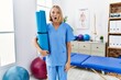 Young caucasian physiotherapist woman holding yoga mat scared and amazed with open mouth for surprise, disbelief face