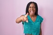 © Krakenimages.com - Young african american with braids standing over pink background pointing displeased and frustrated to the camera, angry and furious with you
