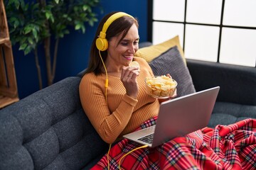 Canvas Print - Middle age woman watching movie eating chips potatoes sitting on sofa at home