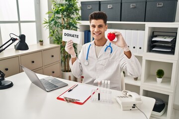 Wall Mural - Young hispanic doctor man supporting organs donations smiling with a happy and cool smile on face. showing teeth.