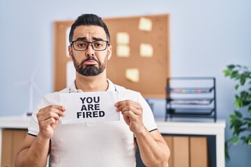 Poster - Young hispanic man with beard holding you are fired banner at the office depressed and worry for distress, crying angry and afraid. sad expression.