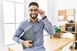 © Krakenimages.com - Young arab man smiling confident holding clipboard at office
