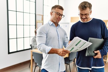 Canvas Print - Two middle age business workers speaking while partners working at the office.