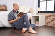 © Krakenimages.com - Young caucasian man reading book sitting on floor at bedroom