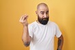 © Krakenimages.com - Young hispanic man with beard and tattoos standing over yellow background doing italian gesture with hand and fingers confident expression
