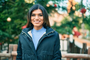 Beautiful hispanic woman smiling confient by christmas decorations