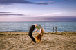 Teenage girl doing back bend on the beach in the evening