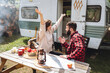 Young beautiful loving couple travelling across country in the van. Millennial man and woman in a travel camper. Cozy atmosphere, vacations vibe. Drinking tea, choosing new destination on a map