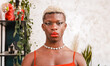 African black transgender model with stylish makeup looking at camera in daytime at home