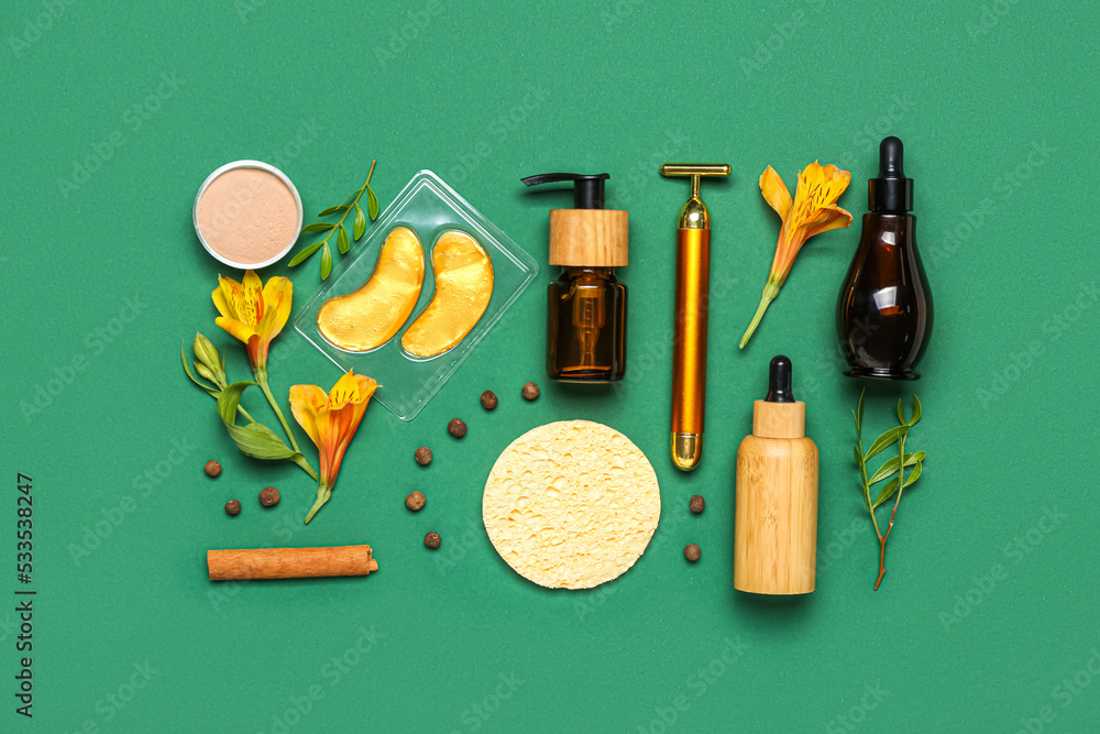 Facial massage tool with cosmetic products and natural components on green background