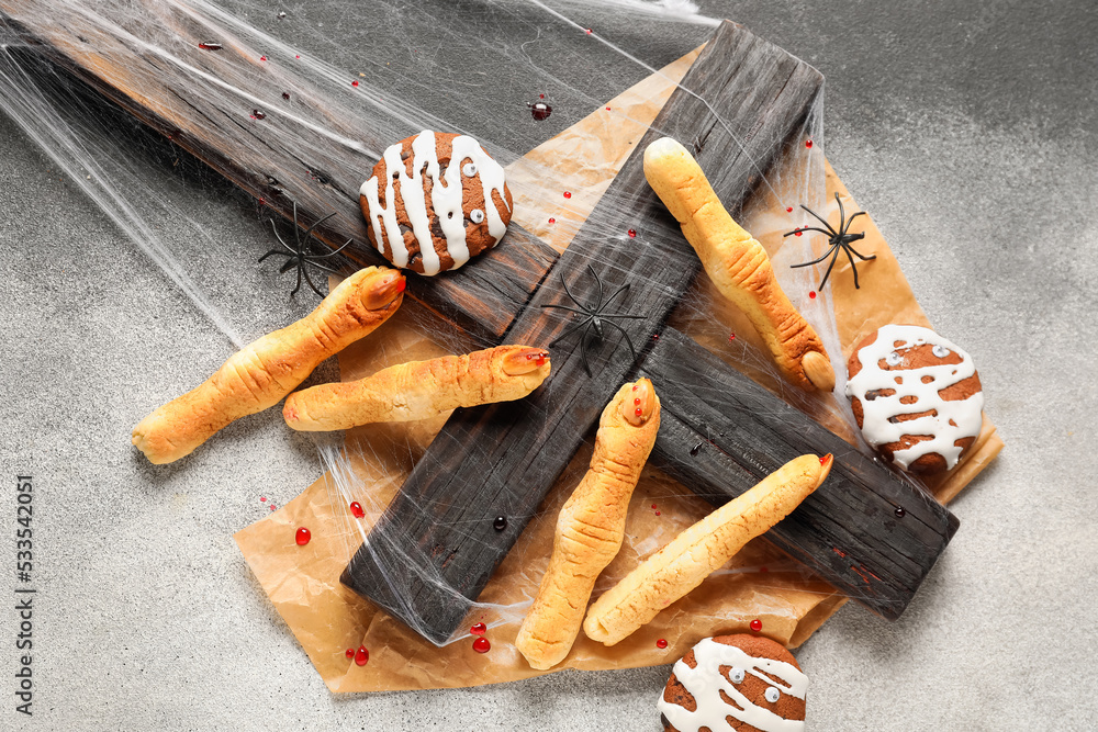 Halloween cookies and cross with baking paper on dark background