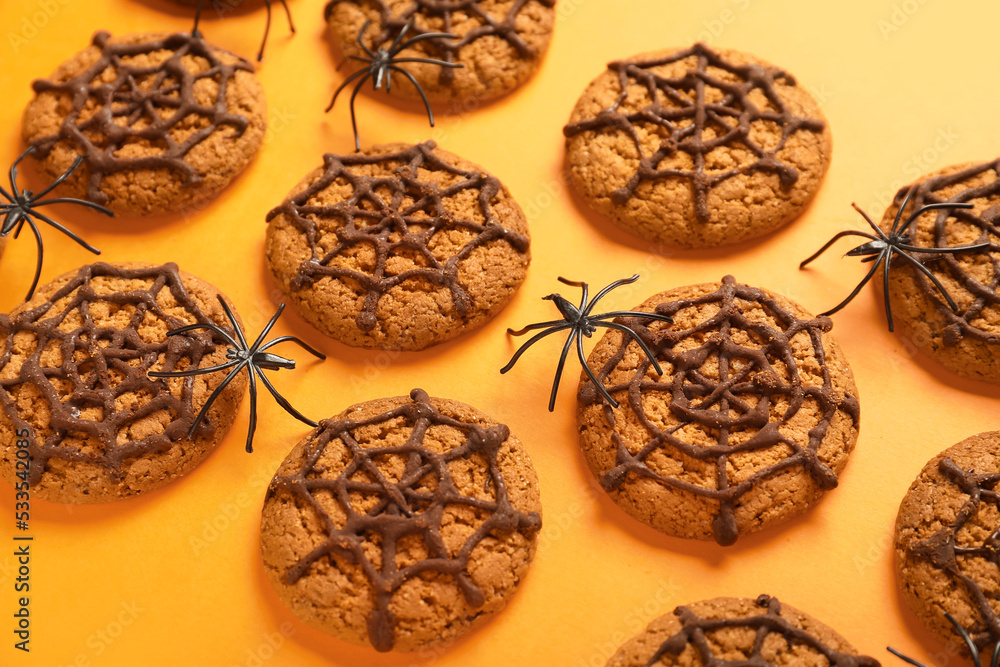 Halloween spiderweb cookies with spiders on orange background, closeup