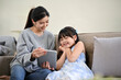 © bongkarn - Asian mom showing something on tablet to her daughter, watching kid's cartoon together