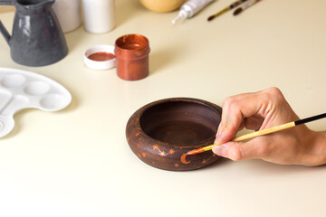 Women paint moon and constellation on pot. Ceramic art class. Decor of Bowl on Workshop. Pottery Hobby concept Craft