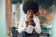© fotofabrika - Portrait of a beautiful young african woman using her cellphone in a cafe