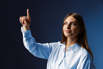 Young female entrepreneur touching virtual screen against grey studio background