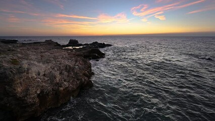 Wall Mural - Amazing video with the sun rising, sea waves and a beautiful rocky coast.