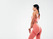© halayalex - Tanned fitness woman in pink sports clothing. Sexy young beautiful model with perfect body.Female isolated on grey background in studio. Stretching out before training