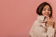 © Look! - Beautiful young caucasian girl is looking at camera holding her jacket collar on pink background. Brunette is wearing beige casual jacket. Place for text, concept