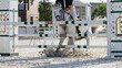 The white horse refuses to jump over the obstacle. A rider in uniform at show jumping competitions. Equestrian accident.