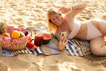 Wall Mural - Cheerful young woman enjoy at tropical sand beach. Young woman taking a picture of fruit on the beach.