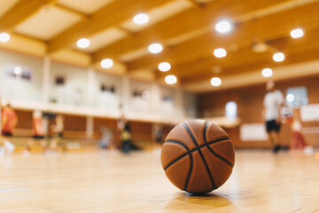 Wall Mural - Basketball Training Game Background. Basketball on Wooden Court Floor Close Up with Blurred Players Playing Basketball Game in the Background.