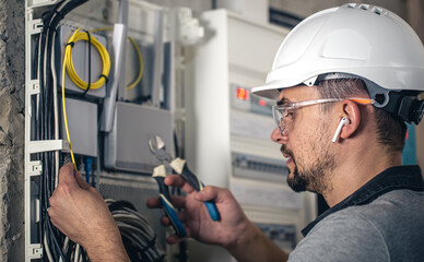 Wall Mural - Man, an electrical technician working in a switchboard with fuses.