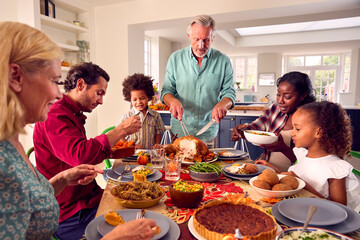 Grandfather Serving As Multi-Generation Family Celebrating Thanksgiving At Home Eating Meal Together