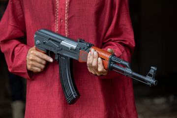 Cropped image of a fighter in red clothing holding a gun on dark background.