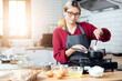 © vacancylizm - Beautiful young woman  is mixing batter, looking at camera and smiling while baking in kitchen at home ,decorating a cake of chocolate cake,cooking class, culinary, bakery, food and people concept