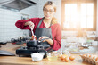© vacancylizm - Beautiful young woman  is mixing batter, looking at camera and smiling while baking in kitchen at home ,decorating a cake of chocolate cake,cooking class, culinary, bakery, food and people concept