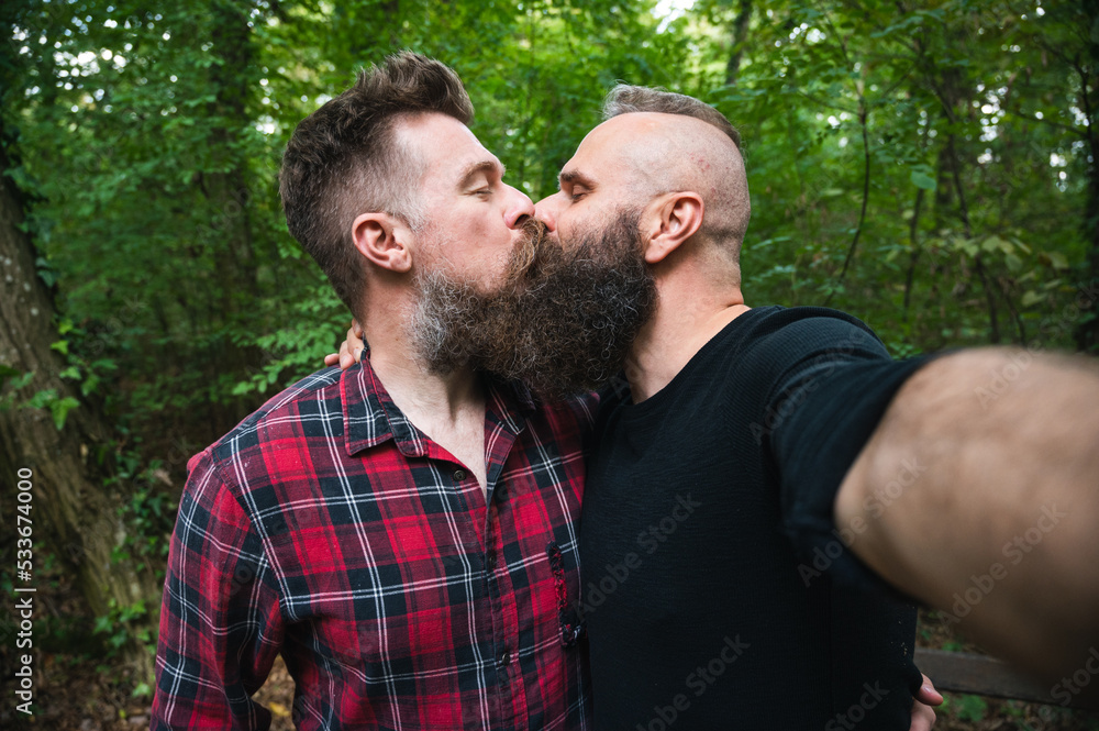 Attractive hipster bearded gay couple taking selfie in the woods. Long ...