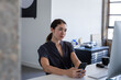 © ReeldealHD images - Businesswoman working at a desktop computer in an office with a smartphone
