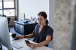 © ReeldealHD images - Businesswoman working at a desktop computer in an office looking at a smartphone