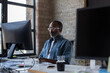 © ReeldealHD images - African American businessman sitting at desk in an office working on a computer