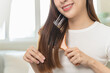 © Pormezz - Happy asian woman brushing hair by wooden comb in the morning.